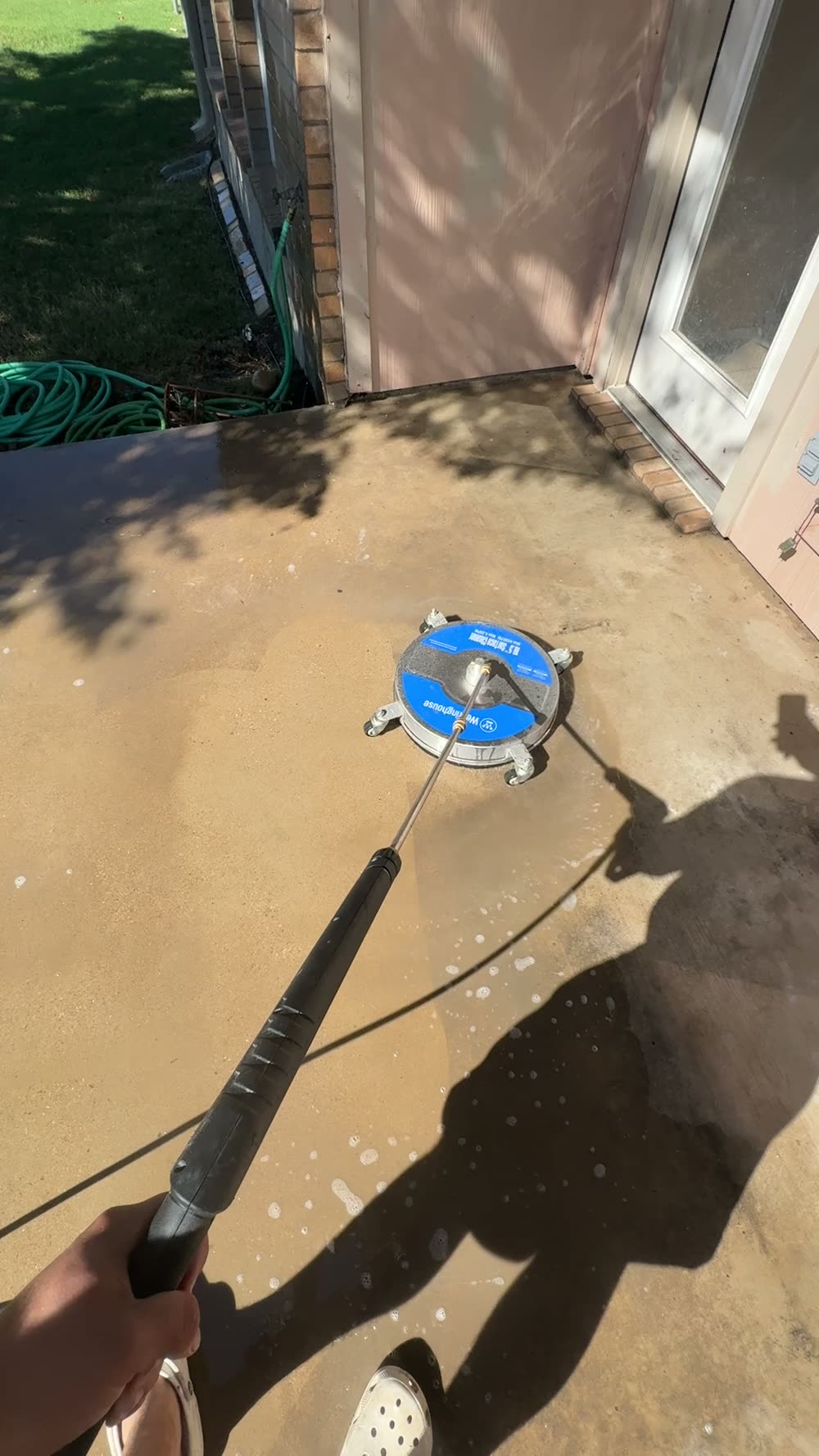 Concrete walkway beside a home being washed, with a clear line between clean and dirty concrete