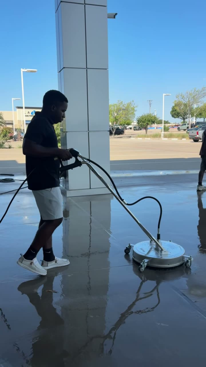 Technician washing a commercial concrete walkway with a surface cleaner