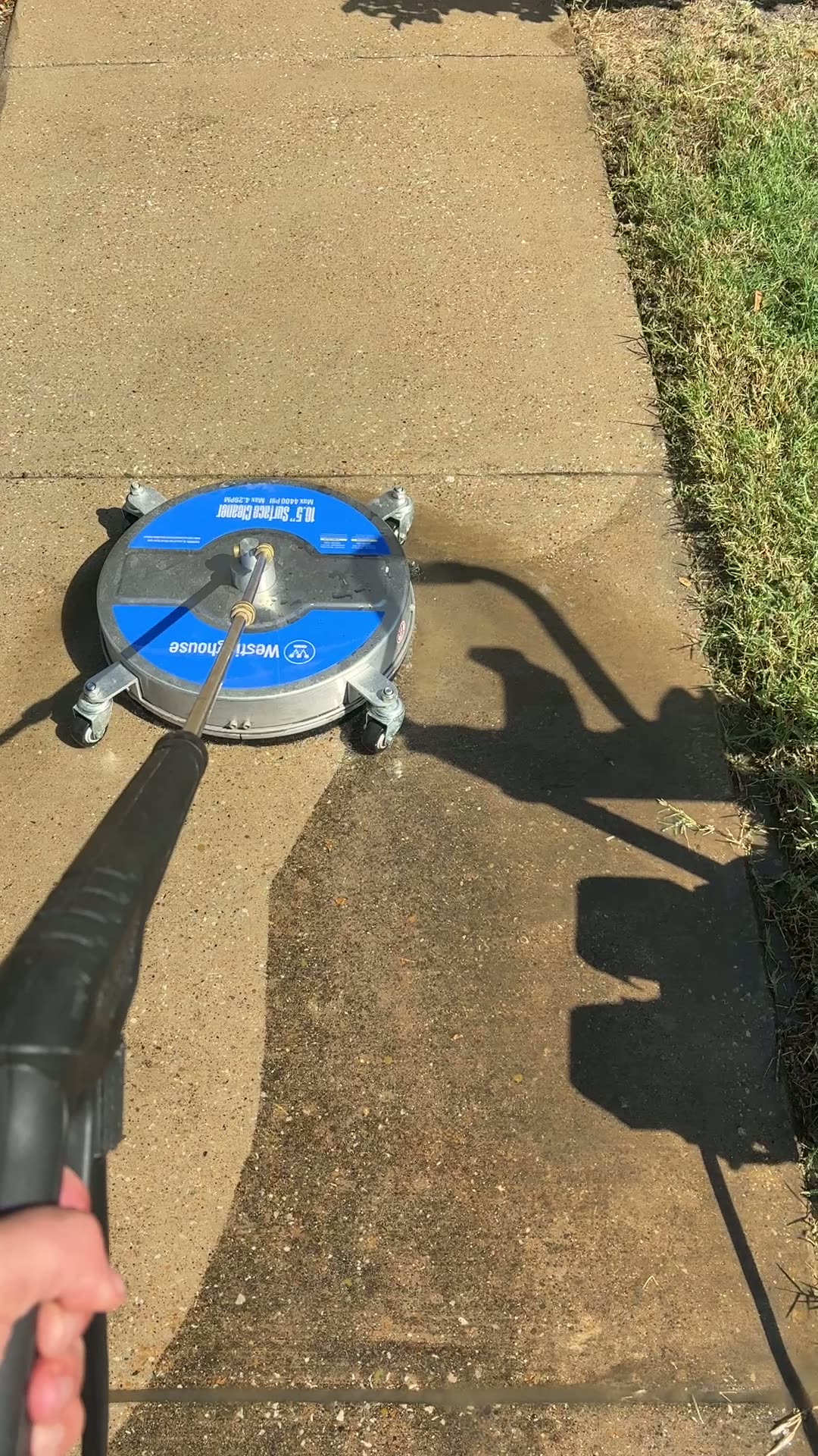 Sidewalk washing in progress with a clear line between the cleaned and uncleaned concrete