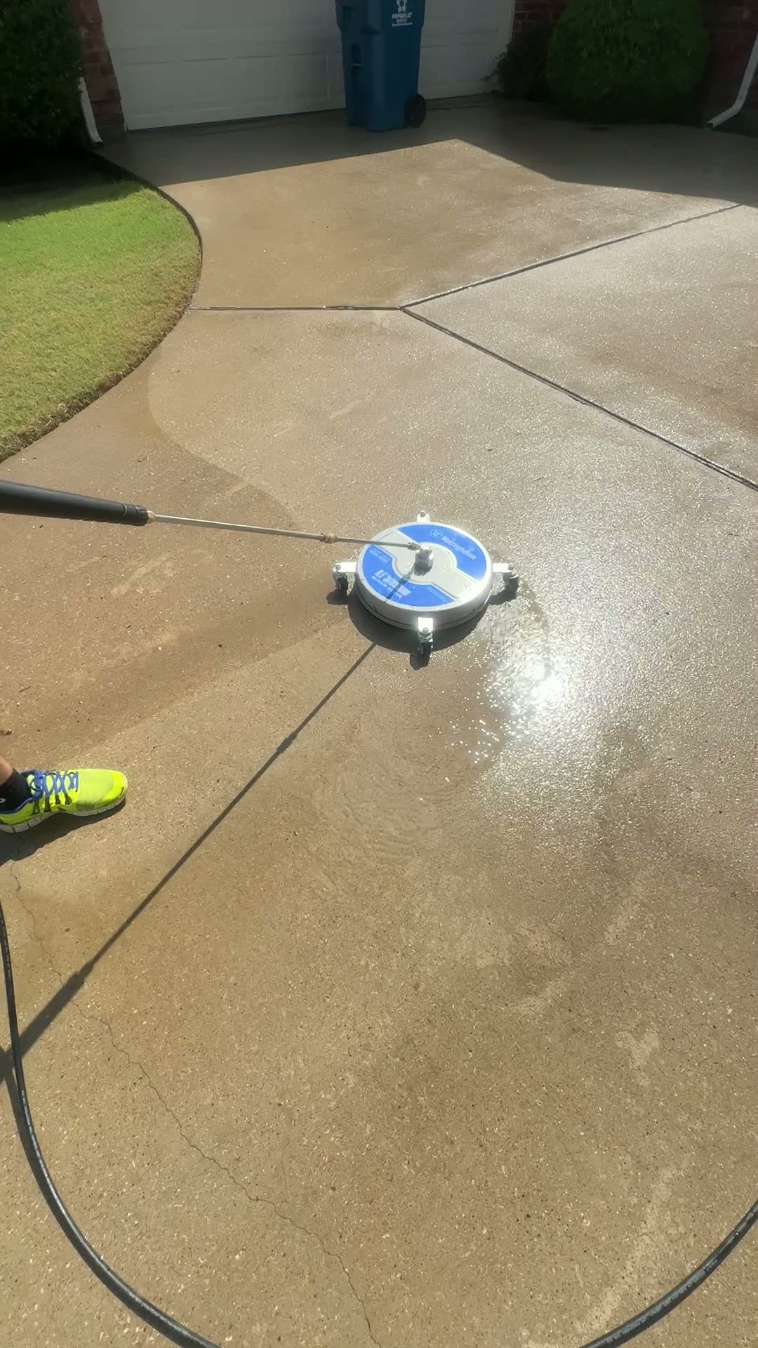 Residential concrete driveway after washing, with water still on the surface