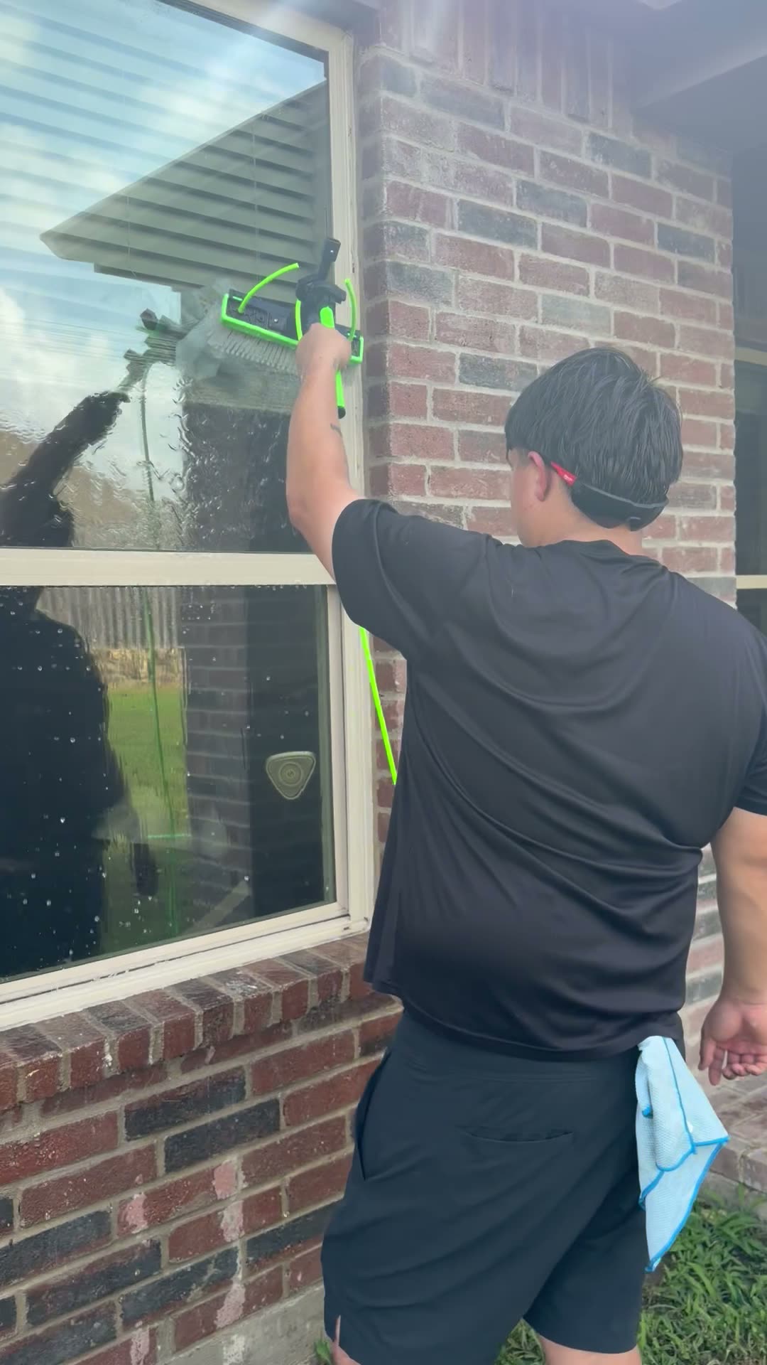 Total Surface Care technician squeegeeing a window on a brick home in the Dallas-Fort Worth area
