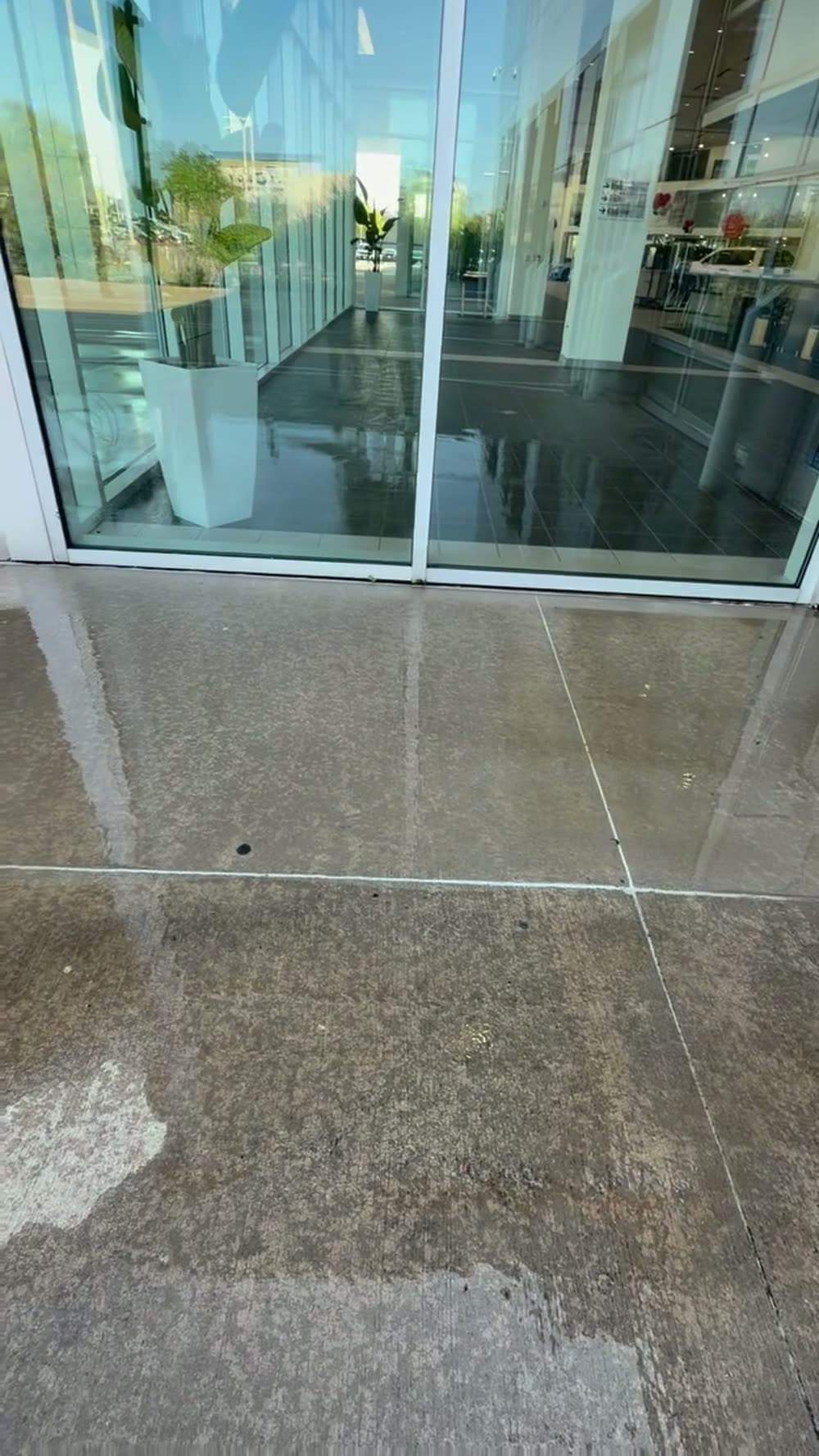 Concrete walkway washed clean outside a glass storefront
