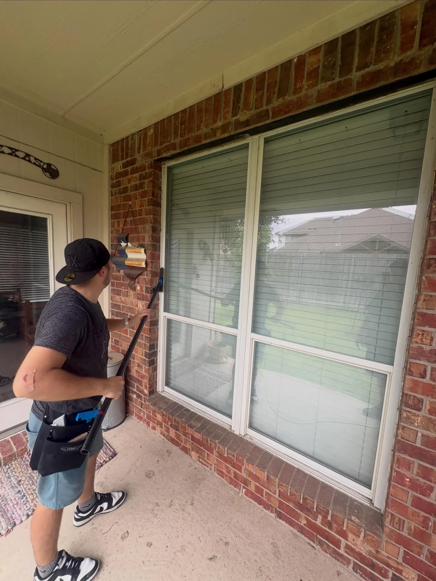Total Surface Care technician cleaning a large covered patio window
