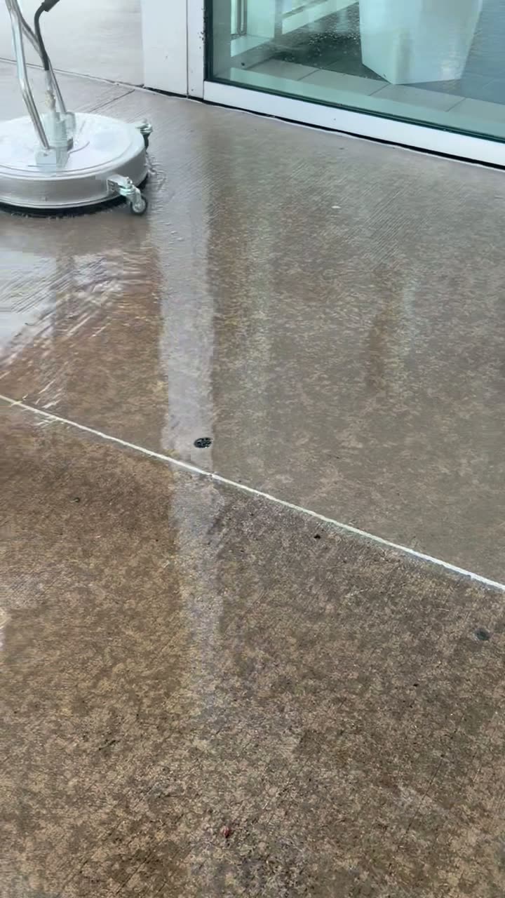 Concrete patio being washed alongside a home with large windows
